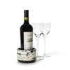 handmade black and cream pattern ojo de pajaro wine bottle coaster with wine bottle inside and two glasses on side