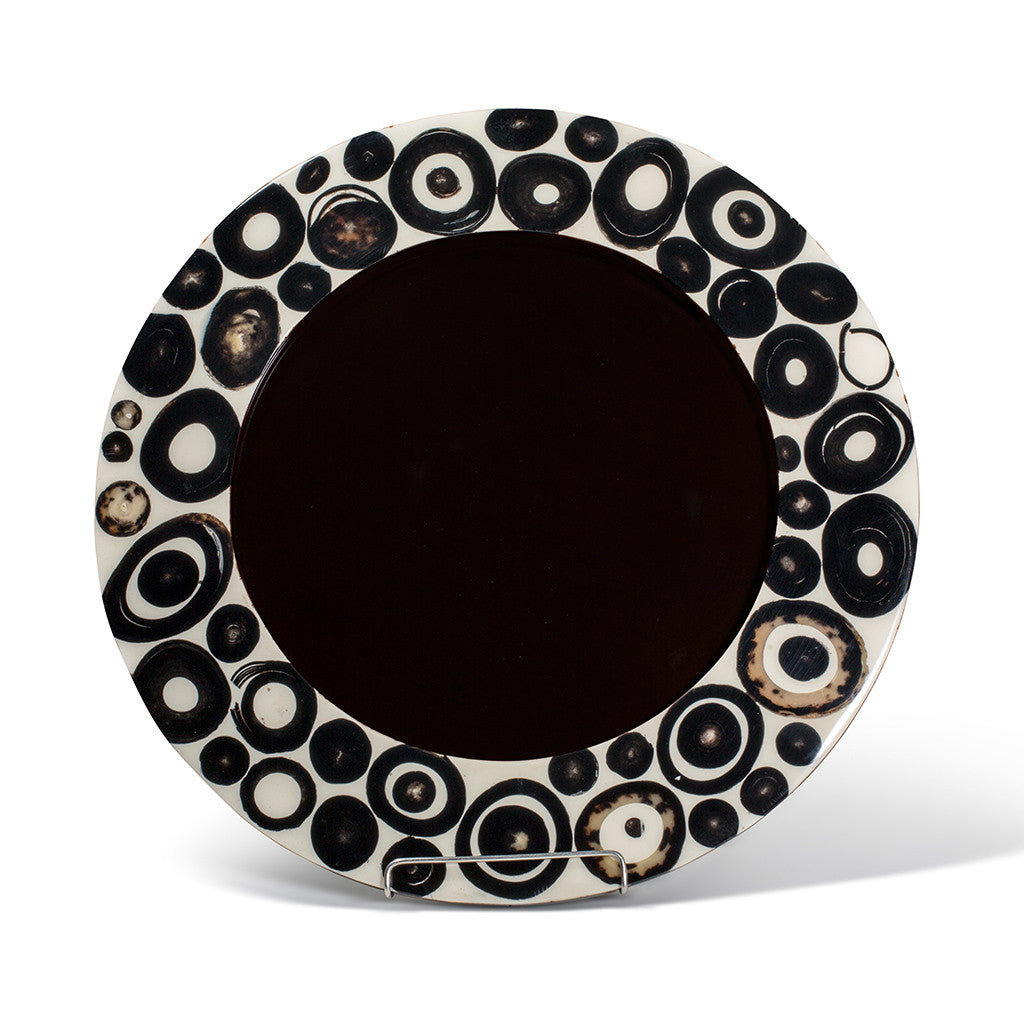 handmade charger plate with circular brown and black horn rings on beige wood